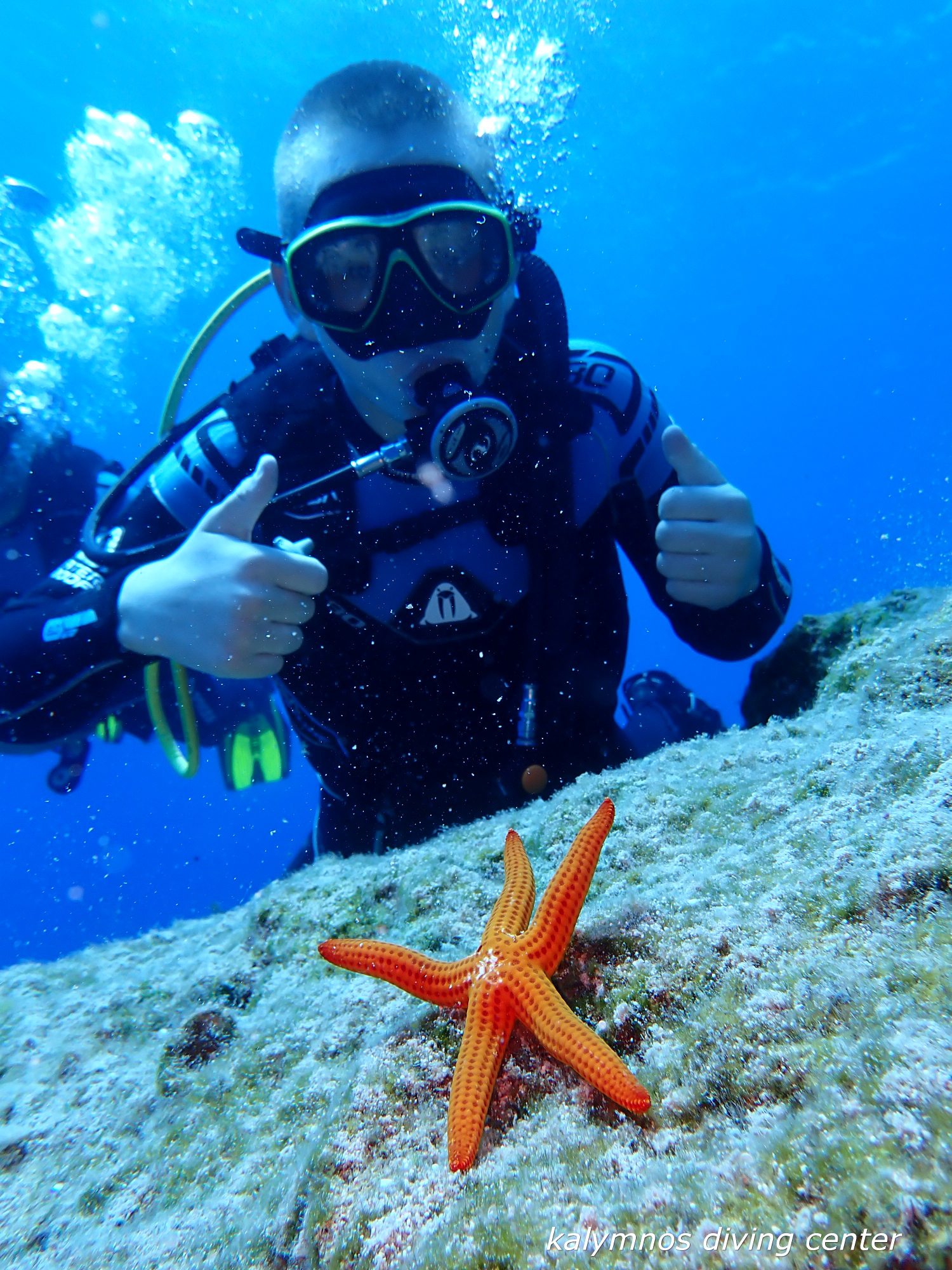 Young diver giving thumbs-up over a starfish
